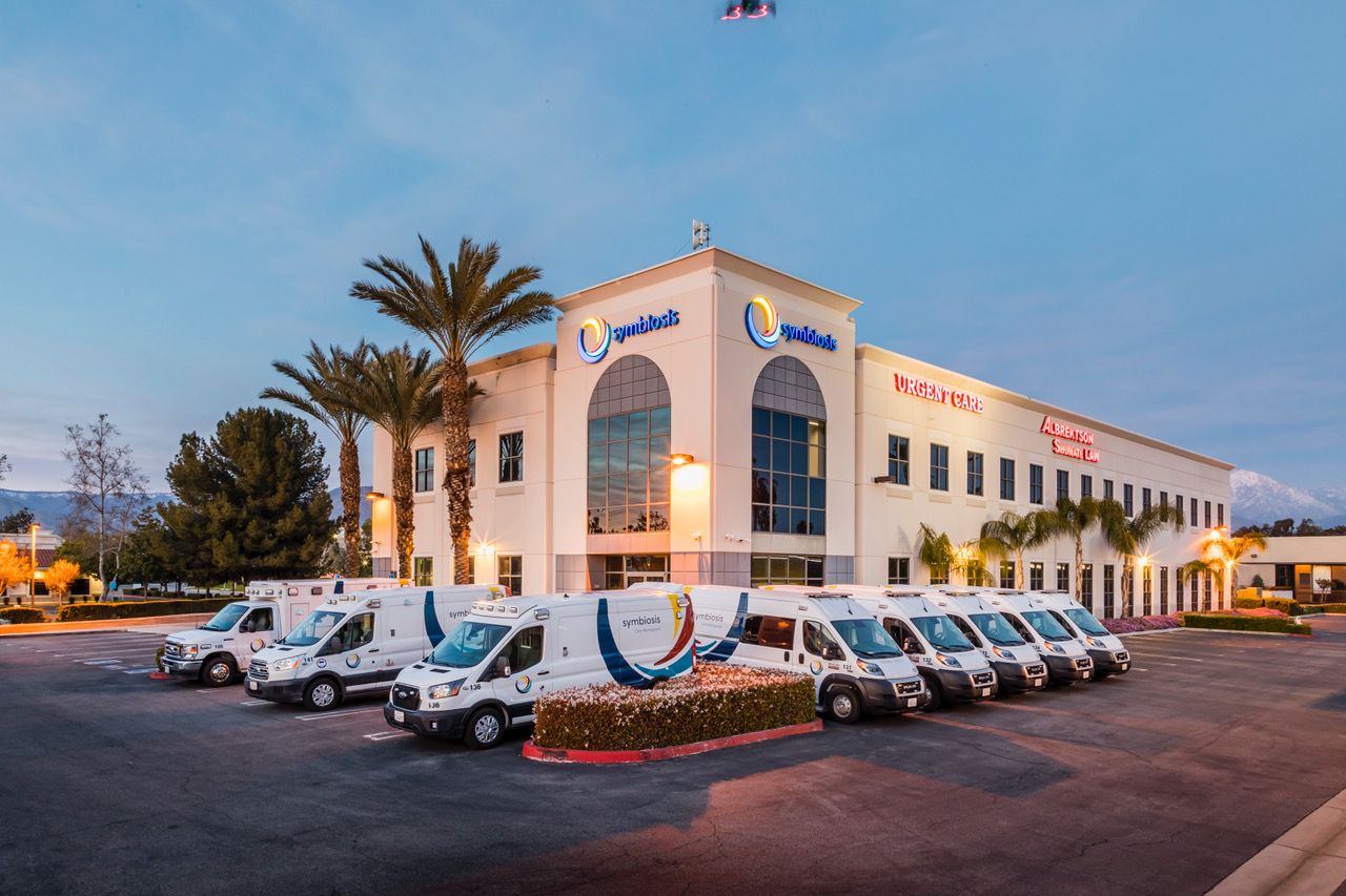 Symbiosis headquarters and Urgent Care building at dusk with the ambulance fleet staged outside