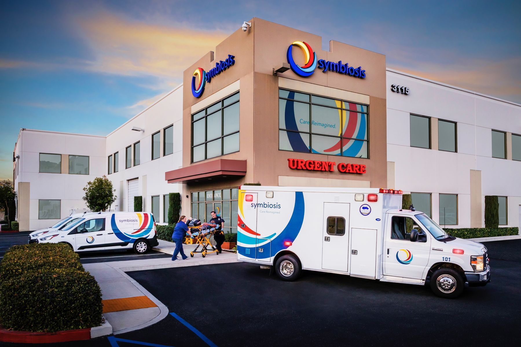 Symbiosis Urgent Care clinic exterior at dusk with ambulances staged outside